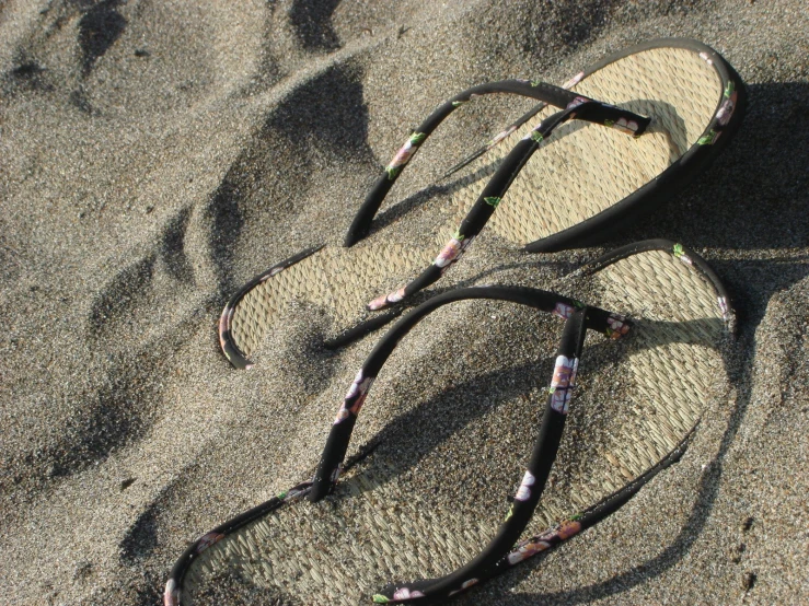 a pair of sandals laying on top of the sand
