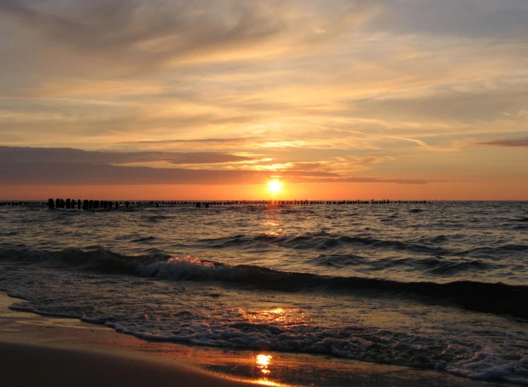 sunset on beach with waves and people in the water