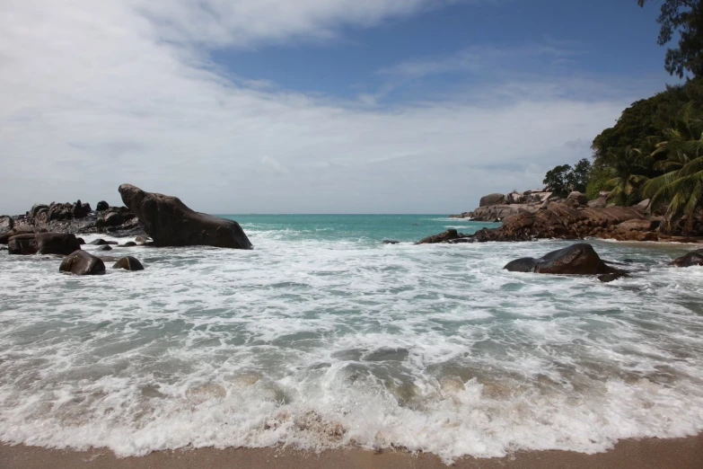 a beach has rough waters and large boulders