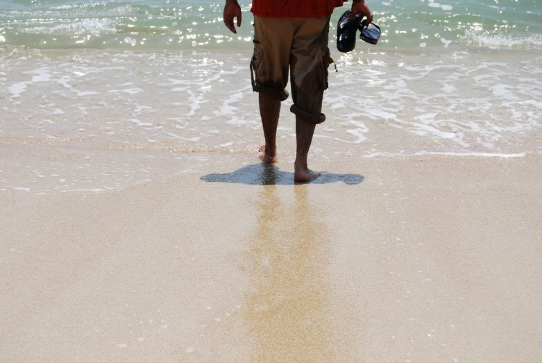 man standing in the sand on a beach looking at the ocean