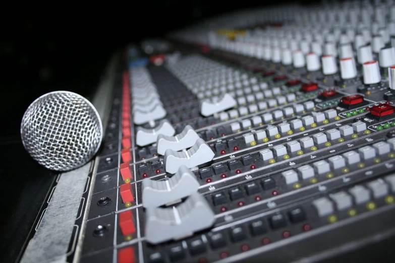 microphone next to sound mixing console in a dark room