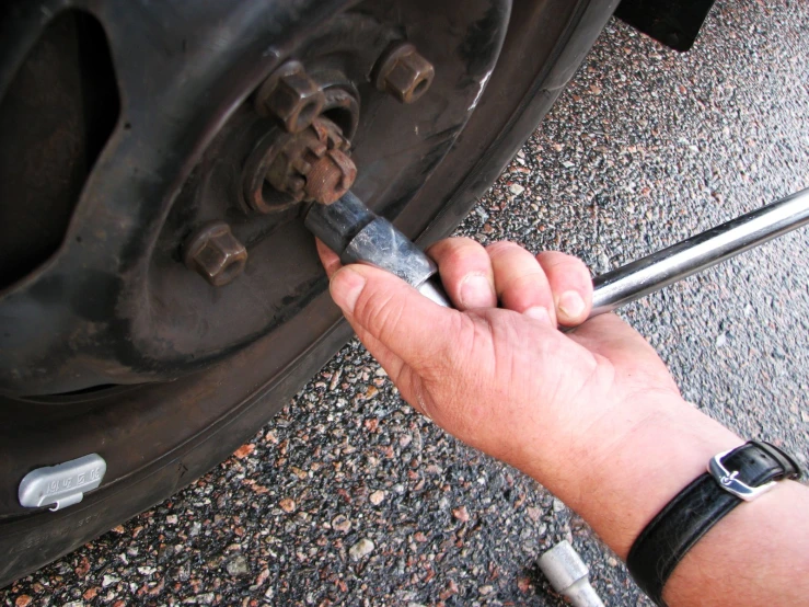 the man holds a wrench to the car tire