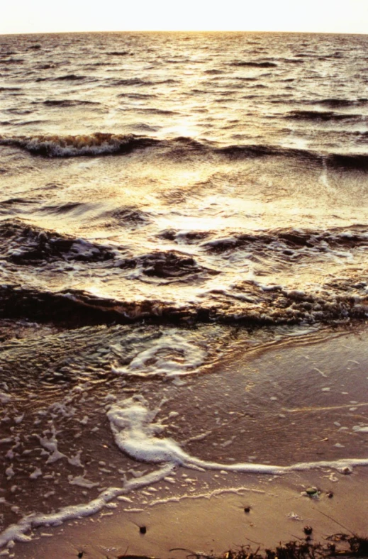 the ocean waves are rushing on a beach