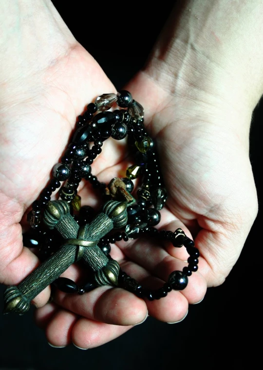 a person holding a small rosary in their hands