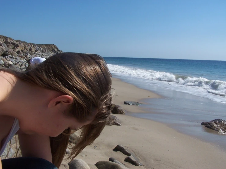 a woman sitting on the sand near the water