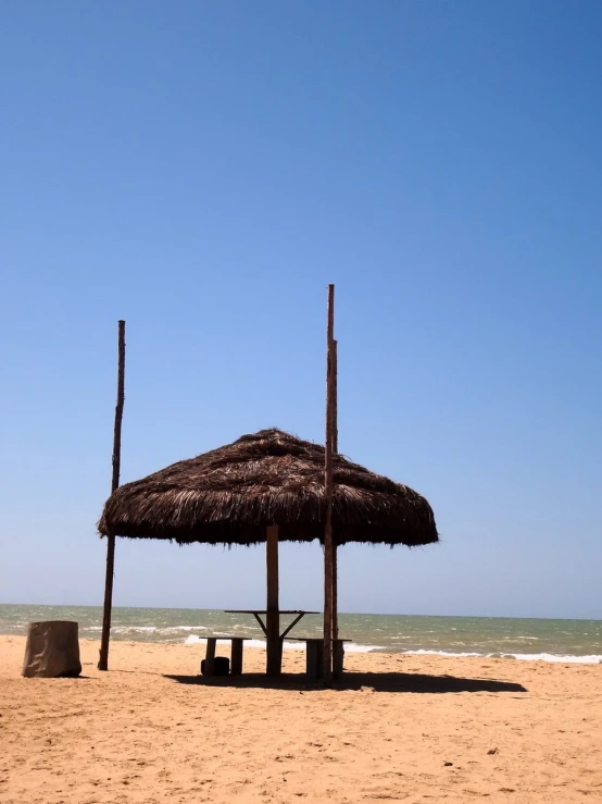 an umbrella, table, and bucket on the beach with no people