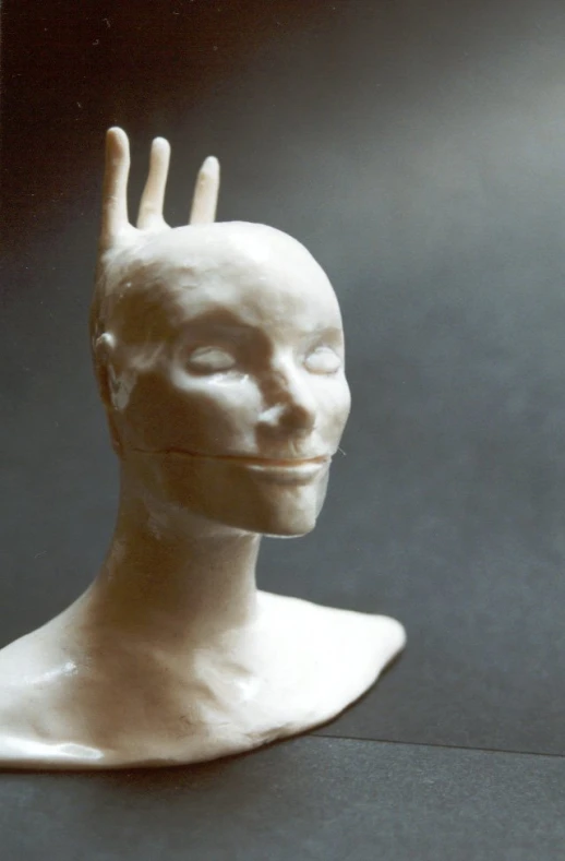 a sculpture of a person's head with one hand in the air