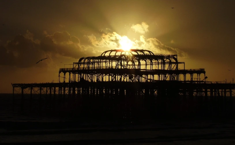 a bird flies past a structure under the sun