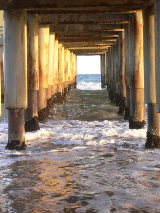 a wooden pier extends out into the ocean from the surf