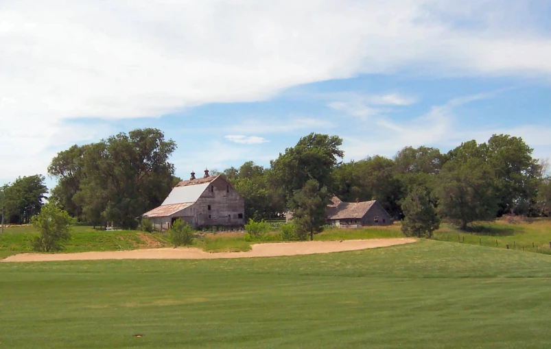 there is a house near a field in the middle of the day