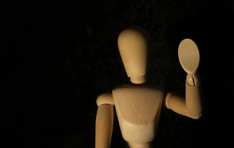 wooden dummy holds a mirror and is holding it in his hand