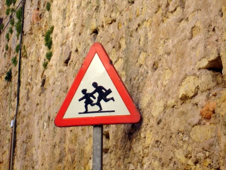 a triangle sign on the side of a stone wall