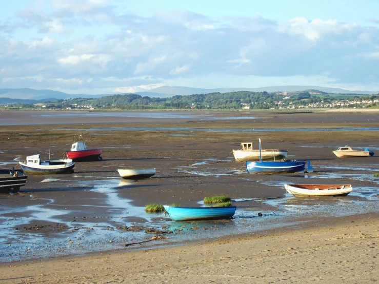 a group of small boats sitting in the mud on a beach