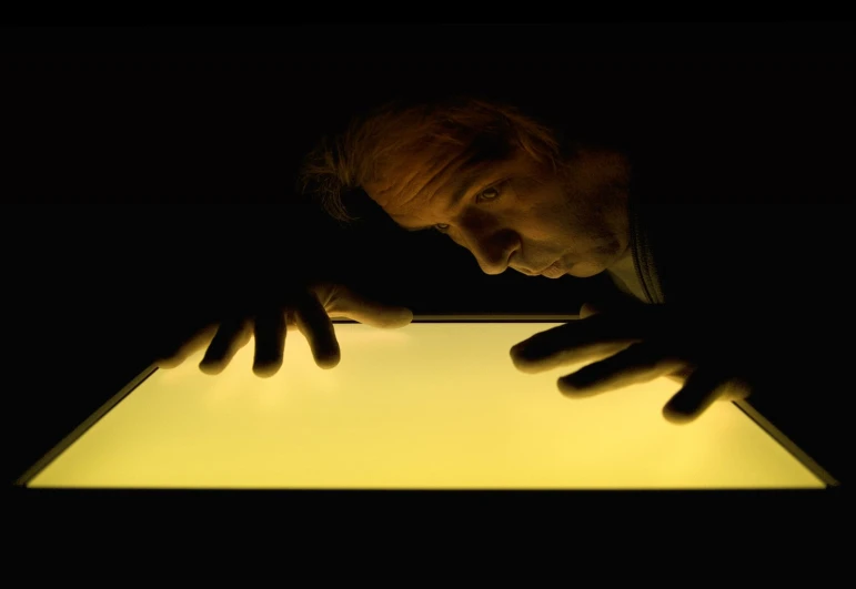 a man staring over a glowing table with his hands on it