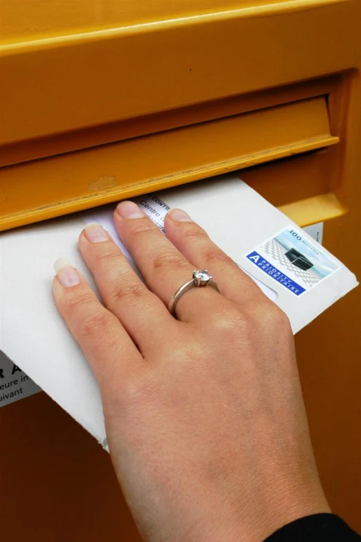 a hand is pressing a mail into a mailbox