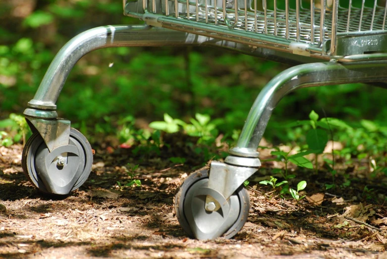 a silver metal dolly in the grass with a basket attached