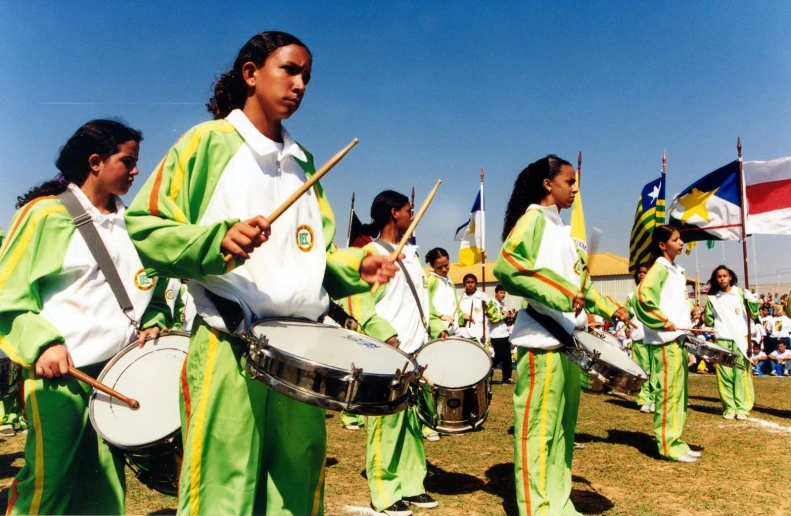 a group of women are playing drums in green clothing