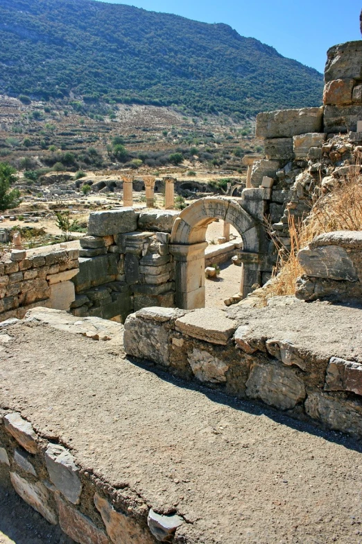 a hill sitting below a stone structure near a forest