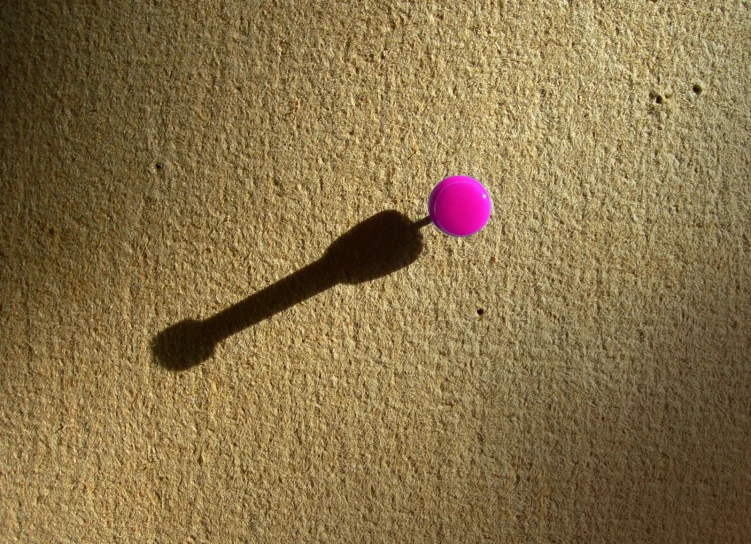 a pink object laying on the ground next to a shadow