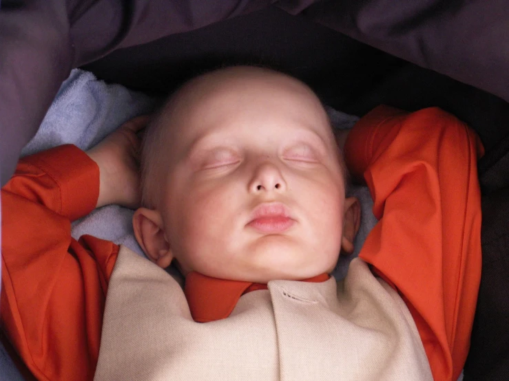 a baby with his head resting on the side of the bed