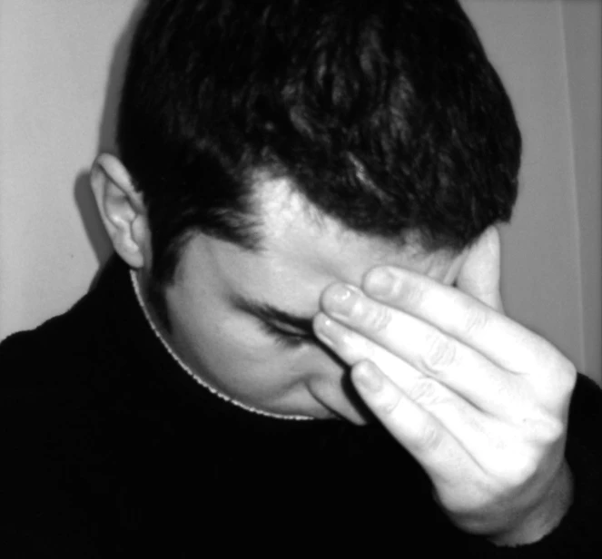 a man covering his eyes with one hand