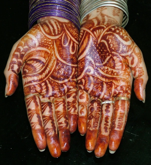 two hands covered with henna, each with different designs