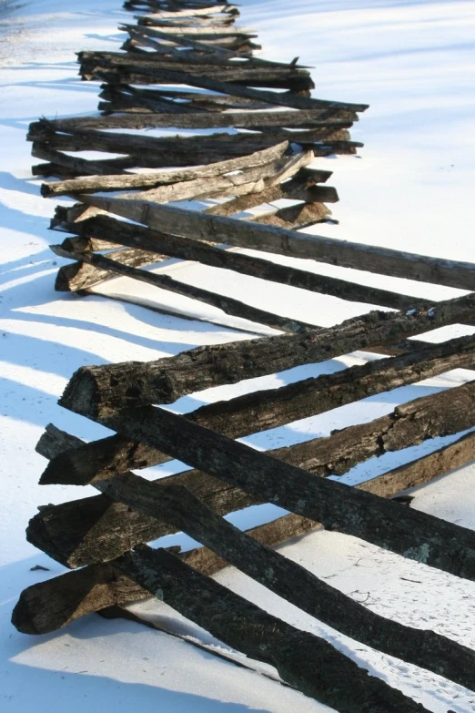 a long wooden fence laying in the snow