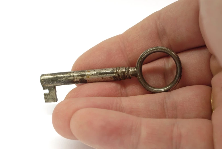someone is holding a vintage key to a tiny keyhole