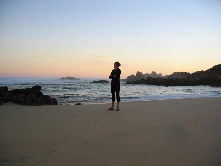 a person that is standing in the sand near the water