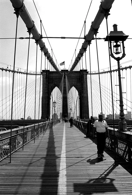 man walking across a wooden bridge over a river