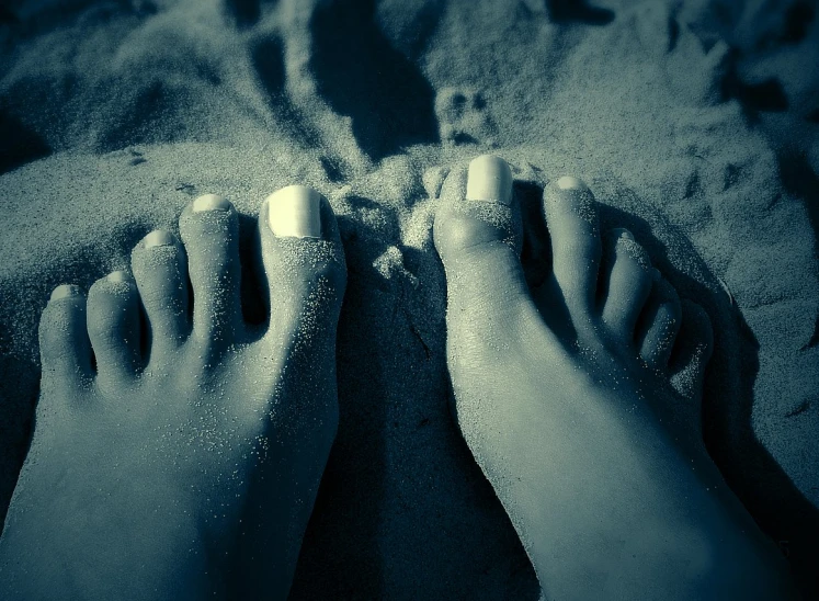 a person sitting in the sand while feet are drawn in the sand