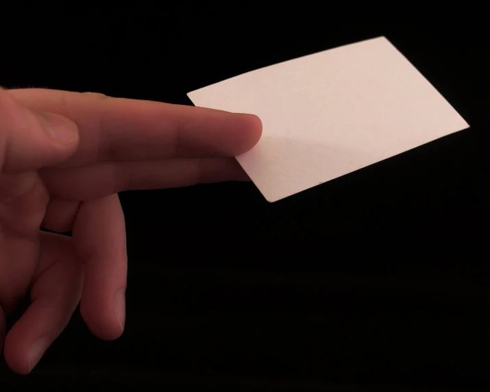 a person holding a piece of white paper in their hand