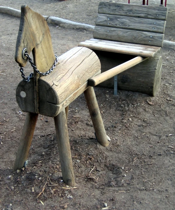 a wooden horse shaped bench with chains hanging from it