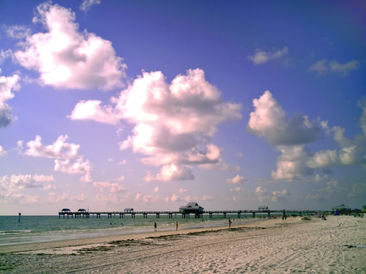 there are people walking on the beach by the pier