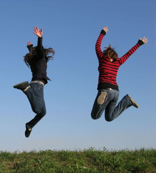 two girls in the air with their arms up as if they were flying through the air