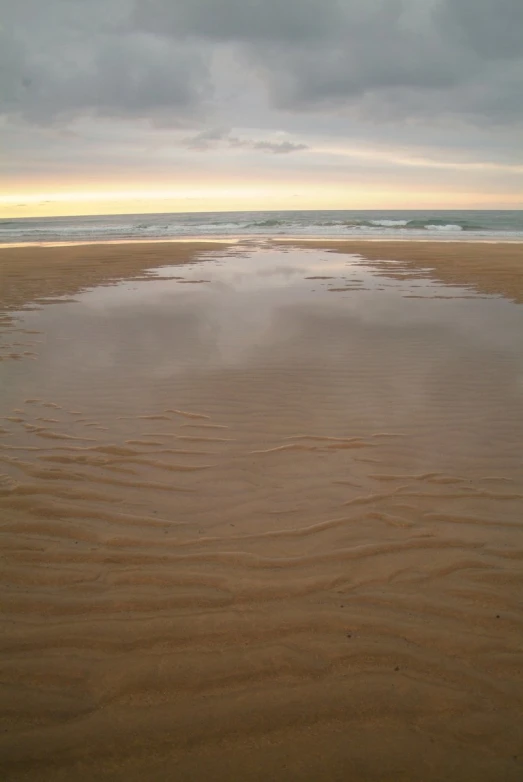 an empty sandy beach sitting under a gray cloudy sky