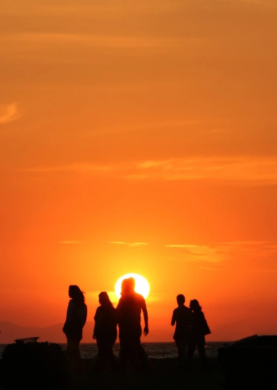 group of people walking along beach during sunset