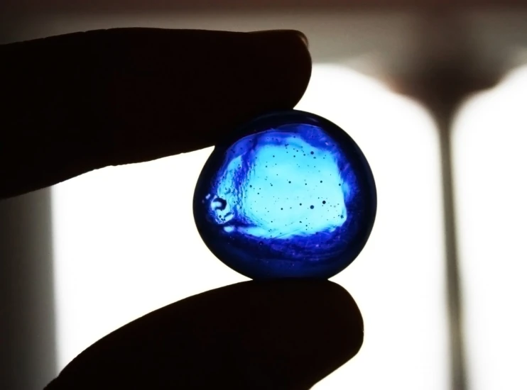 a person holds a piece of blue colored glass