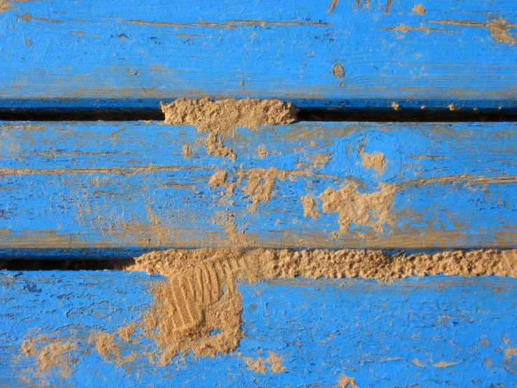 blue wooden planks with sand on top of them