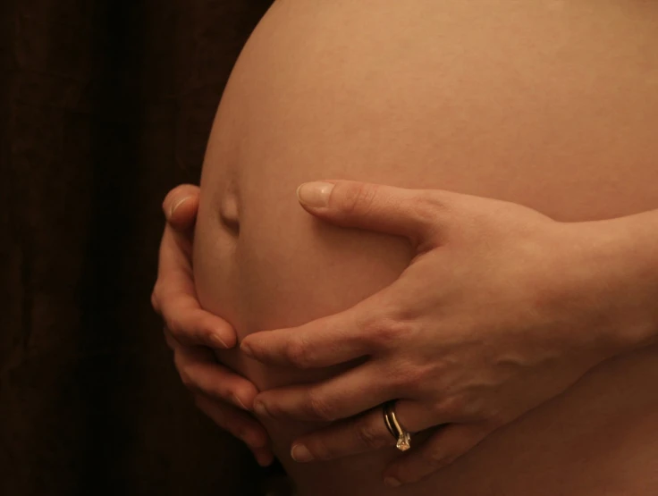 a pregnant woman's belly, holding her hand on the pregnant's stomach