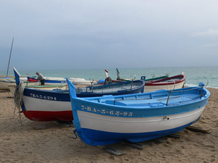 boats parked on the shore with ocean in the background