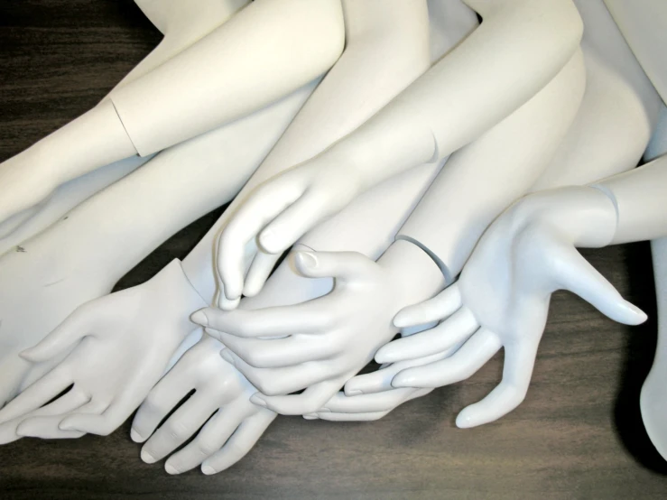 a pile of mannequin heads holding hands over each other