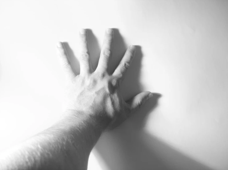 two hands touching each other and resting against a wall