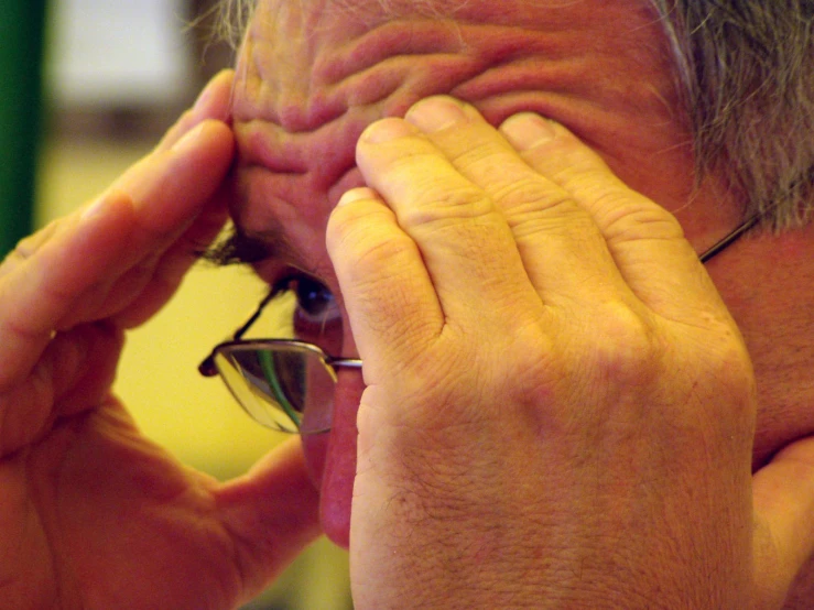 a man putting soing up to his eye with his hands
