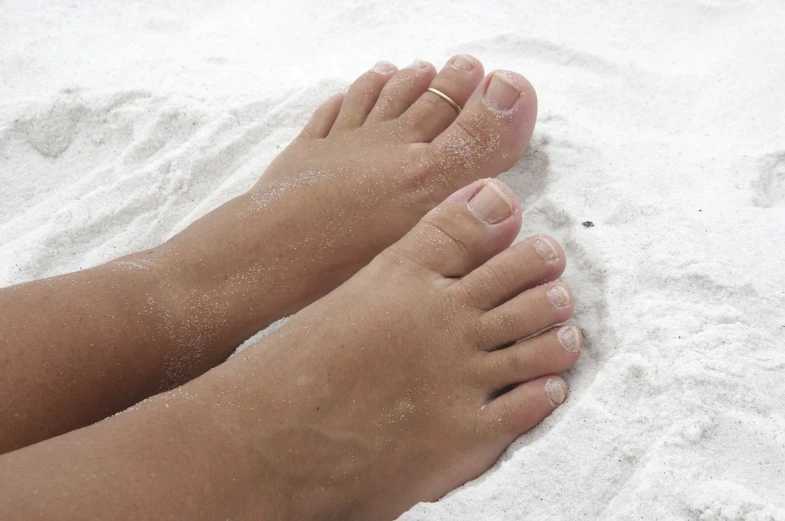 a person has their bare feet and toe on white sand