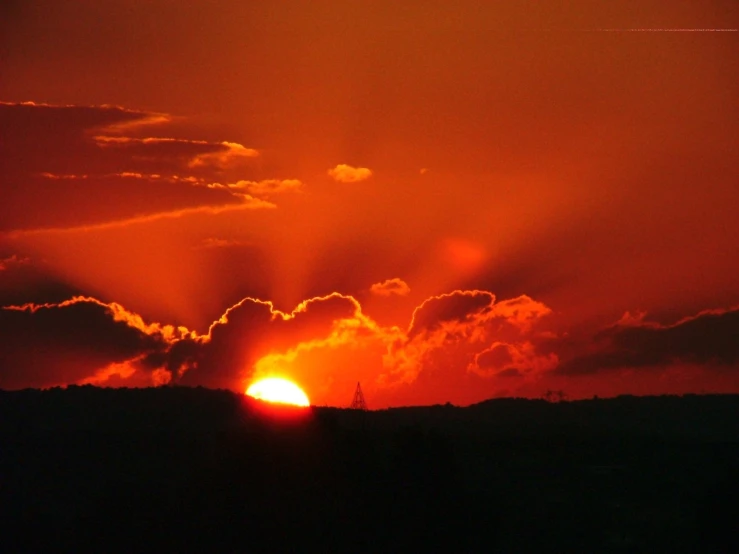 the sun is setting behind clouds on a cloudy day