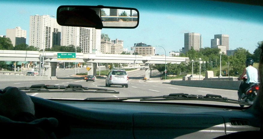 inside a vehicle is a view from inside the car looking at cars and an exit way