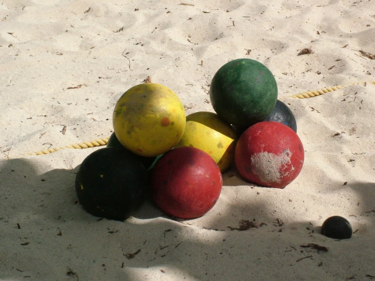 a pile of beach balls sits in the sand