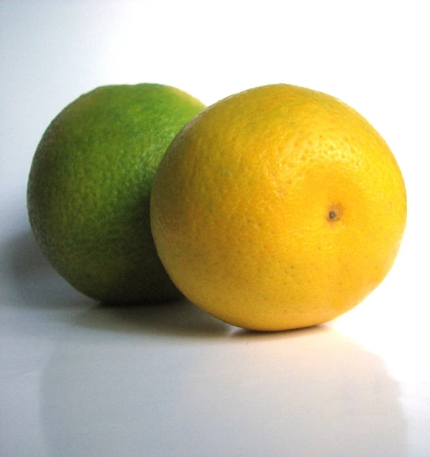 two citrus fruits that are on a white surface