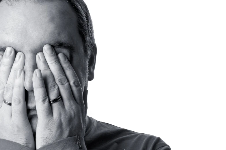 man covering his mouth with hands while looking back